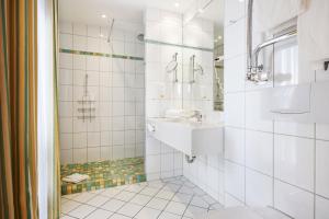 a white bathroom with a sink and a shower at Strandhotel Sylt Westerland in Westerland