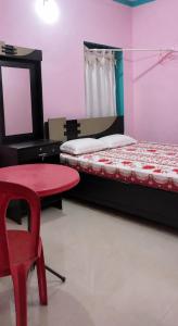 a room with a bed and a table and a red chair at Rose Villa Kovalam in Kovalam