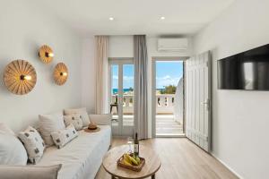 ein weißes Wohnzimmer mit Sofa und Tisch in der Unterkunft Almiriki Naxos Beachside Living in Plaka