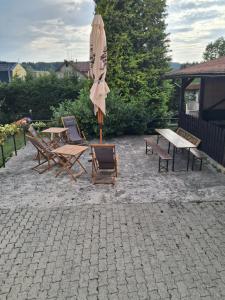 a patio with a table and chairs and an umbrella at Penzion Krušnohorka in Tatrovice