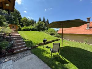 a lawn with a chair and an umbrella in a yard at Altum Mátra Vendégház in Mátraszentimre