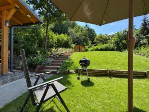 a yard with a grill and a chair and an umbrella at Altum Mátra Vendégház in Mátraszentimre