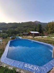 a large blue swimming pool with a house in the background at Ruby Bungalow Alanya in Yaylalı
