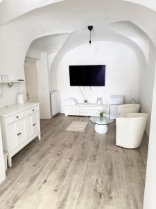 a white living room with wooden floors and a flat screen tv at Penzion Florián Telč in Telč