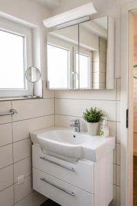 a white bathroom with a sink and a mirror at Zugvogel EG in Wangerland +15 photos