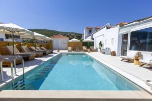 a swimming pool with chairs and a villa at Laza Beach in Skala