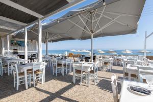 a restaurant with white tables and chairs and the ocean at Laza Beach in Skala