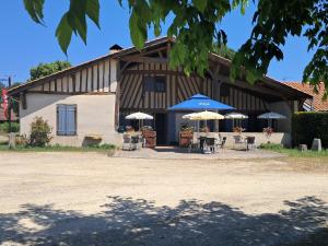 a building with tables and umbrellas in front of it at L'auberge Chris and Chris in Retjons