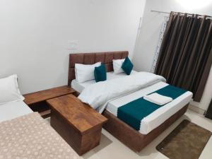 a bedroom with two beds and a table and a couch at Uttarkashi Resort in Uttarkāshi