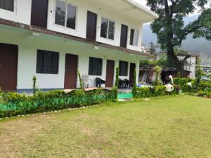 a house with a lawn in front of it at Uttarkashi Resort in Uttarkāshi