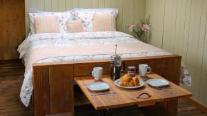 a bed with a table with a tray of food on it at Bertha Shepherd's Hut in Lydney