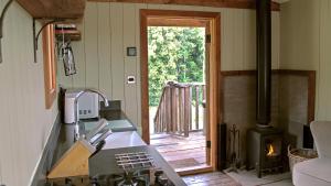a kitchen with a stove and an open door at Bertha Shepherd's Hut in Lydney