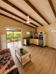 a living room with a ceiling fan and a kitchen at Gîte Avocatier - Villa Marina in Bouillante