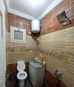 a bathroom with a toilet and a tv on a wall at Sami apartment in Alexandria