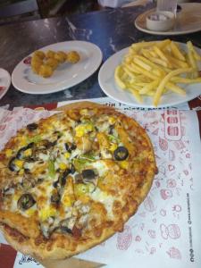 a pizza sitting on top of a table with plates of fries at Sami apartment in Alexandria