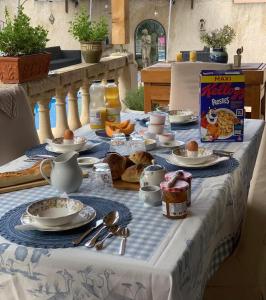 a table with breakfast food on a blue and white table cloth at Les Menendos in Saint-Jean-de-Barrou