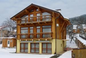 een groot houten huis met een balkon in de sneeuw bij Chalet Mont Blanc in Jaremtsje