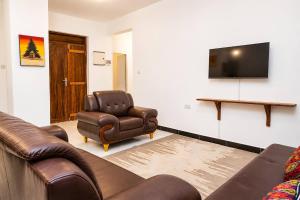 a living room with a couch and a chair and a flat screen tv at Uroa Beachfront Apt Direct Sand in Uroa