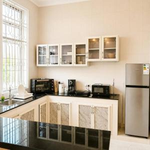 a kitchen with white cabinets and a stainless steel refrigerator at Uroa Beachfront Apt Direct Sand in Uroa