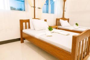two wooden beds in a room with windows at Uroa Beachfront Apt Direct Sand in Uroa