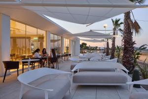 a restaurant with white beds and people sitting at tables at Garden Hotel Ripa in Vieste