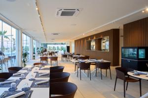 a restaurant with tables and chairs and windows at Garden Hotel Ripa in Vieste