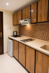 a kitchen with wooden cabinets and a sink and a microwave at فندق مرجانة الحجاز مكة المكرمة in Mecca