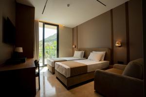 a bedroom with two beds and a couch and a window at Carpe Diem Hotel in Borsh
