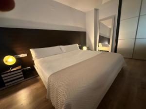 a bedroom with a large white bed and a mirror at Puerta de Africa in Ceuta