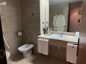 a bathroom with a sink and a toilet and a mirror at Puerta de Africa in Ceuta