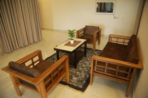 a living room with chairs and a table and a couch at Rivayn Suites in Thiruvalla