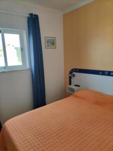 a bedroom with a orange bed and a window at Residencia Laranjeira in Odeceixe
