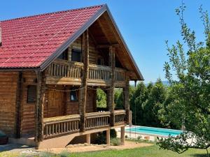 a log cabin with a red roof and a pool at Pine House - Holiday Home in Banja Luka