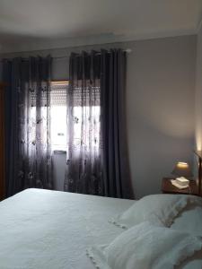a bedroom with a bed and a window with curtains at Casa da Maria in Amoreira