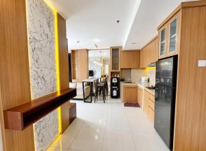 a kitchen with wooden cabinets and a black refrigerator at Pentapolis Apartment Balikpapan Superblock LT4 in Balikpapan