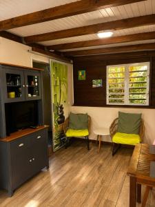 a living room with two chairs and a television at Gîte Bananier - Villa Marina in Bouillante