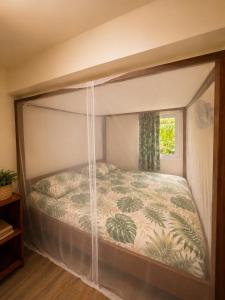 a canopy bed in a bedroom with a window at Gîte Bananier - Villa Marina in Bouillante
