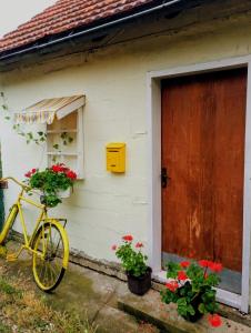 a yellow bike parked next to a house with flowers at Kuća iz zavičaja in Kuršumlija
