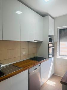 a white kitchen with white cabinets and a window at Apartman Lala in Sarajevo