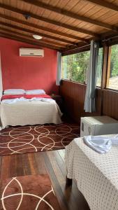 zwei Betten in einem Zimmer mit roter Wand in der Unterkunft Biergarten Hostel in Abraão