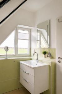 a bathroom with a white sink and a window at Zugvogel OG in Wangerland +16 photos