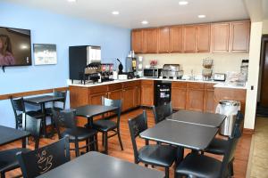 a restaurant with tables and chairs and a kitchen at Baymont Inn And Suites by Wyndham Platteville in Platteville