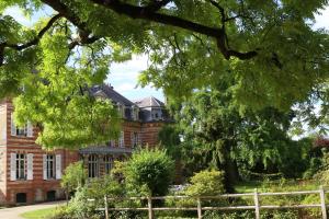 an old brick house with a tree in the foreground at Chambre d'hôtes du Château de Digeon in Morvillers-Saint-Saturnin
