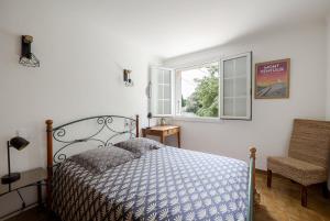 a bedroom with a bed and a window and a chair at Maison de campagne mas Célestin in Camaret-sur-Aigues +8 photos