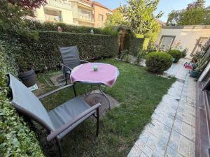 a pink table and chairs in a yard at Safely located apartment in Prishtinë