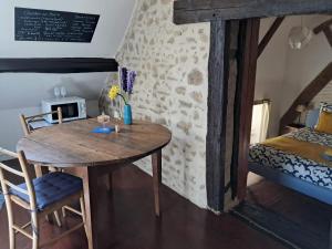 a room with a wooden table and a bed and a table and chairs at Le Monticule in Tardes +14 photos