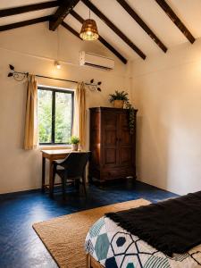 a bedroom with a desk and a table and a window at Lax Stays Morjim by SevenTales in Morjim +4 photos