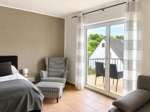 a bedroom with a bed and a chair and a balcony at Rheinview Sunset in Urbar in Urbar