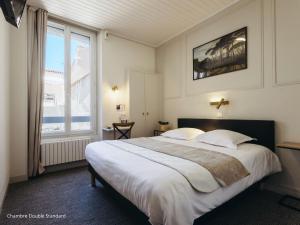 a bedroom with a large bed and a large window at Hotel de Paris in La Rochelle