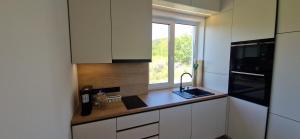 a kitchen with white cabinets and a sink and a window at Forest Nest - Livezeni in Livezeni +4 photos